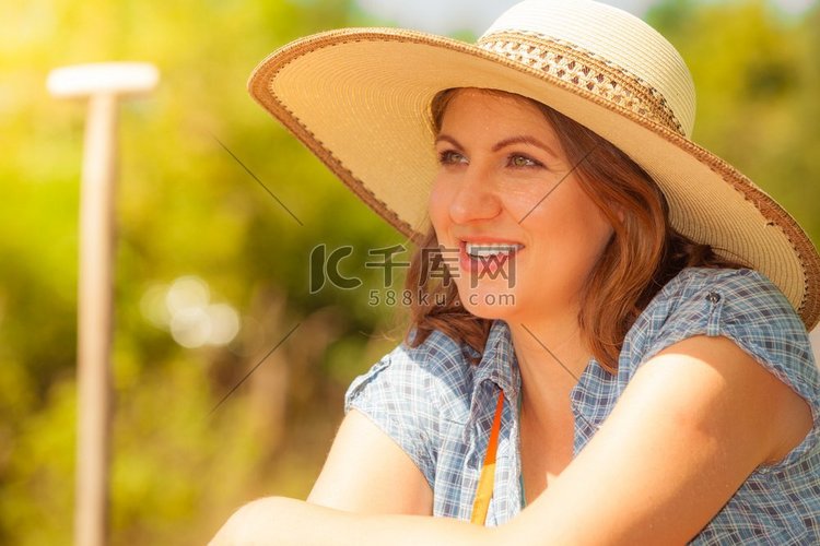花园里戴着大草帽的成熟微笑女子
