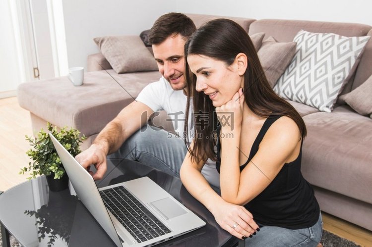 微笑的年轻夫妇使用笔记本电脑家