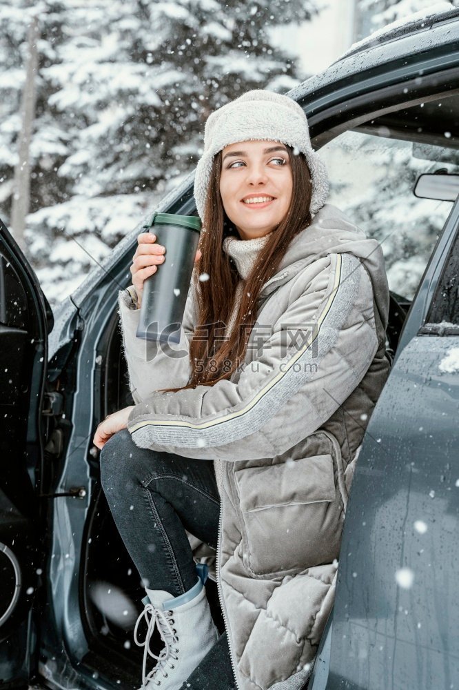 微笑的女人享受雪而公路旅行