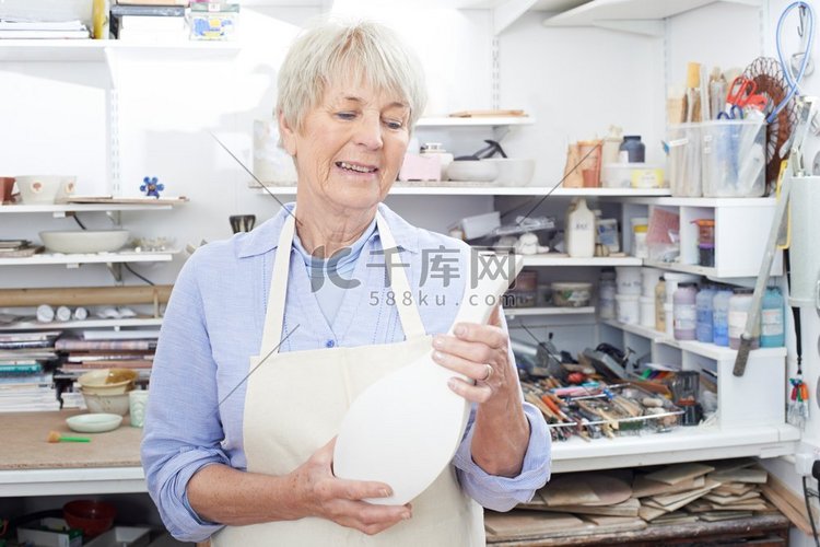 陶艺室里拿着花瓶的老妇人