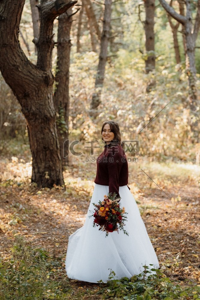 女孩在一个结婚礼服在秋天森林对
