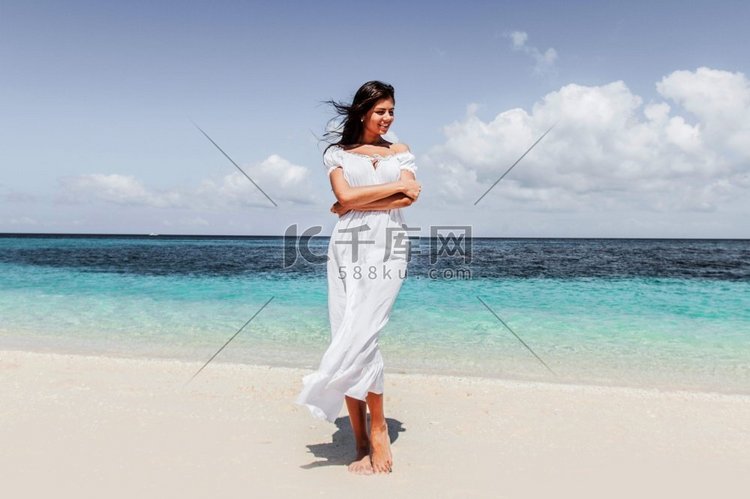 走在热带海滩的白色礼服的妇女，