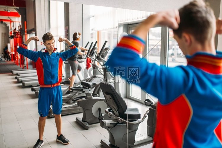 瘦男子在运动服手表他的肌肉在镜