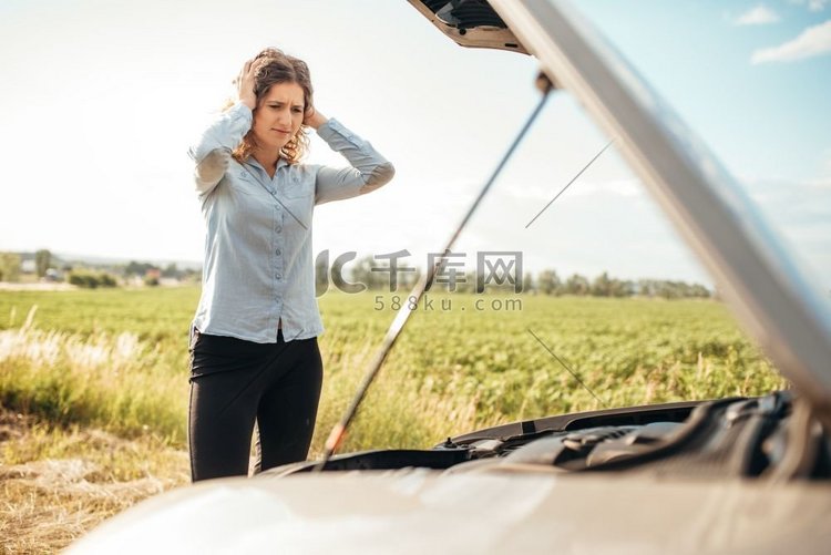 沮丧的女人看着发动机，破车与打
