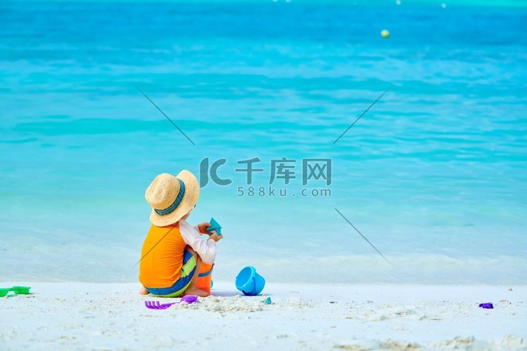 三岁的蹒跚学步的男孩在海滩上玩