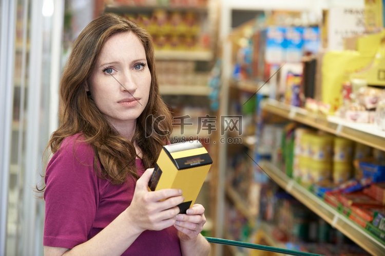 一名妇女在超市查看包装盒上的食