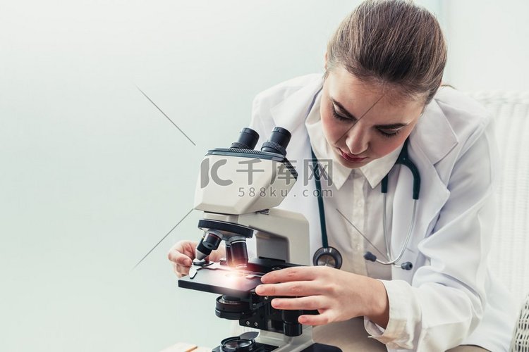 在医院实验室使用显微镜的年轻女
