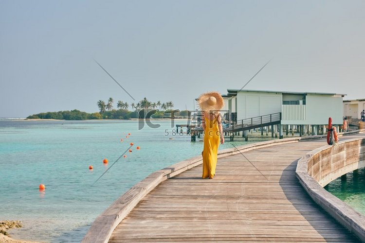 穿着连衣裙的女人走在热带海滩的