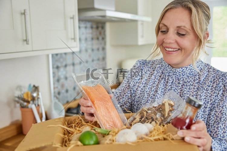 妇女打开在线餐食品食谱套件送到