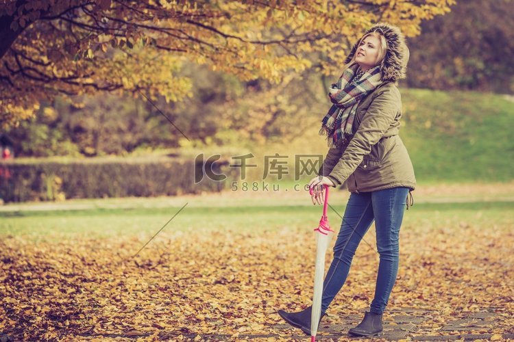 妇女走在公园在金色秋天天气，享
