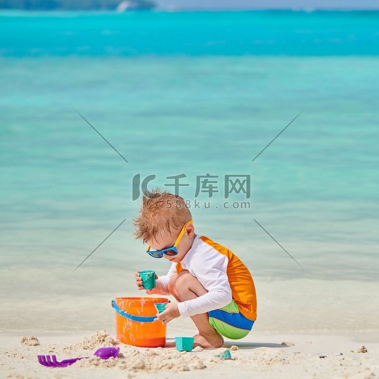 三岁的蹒跚学步的男孩在海滩上玩