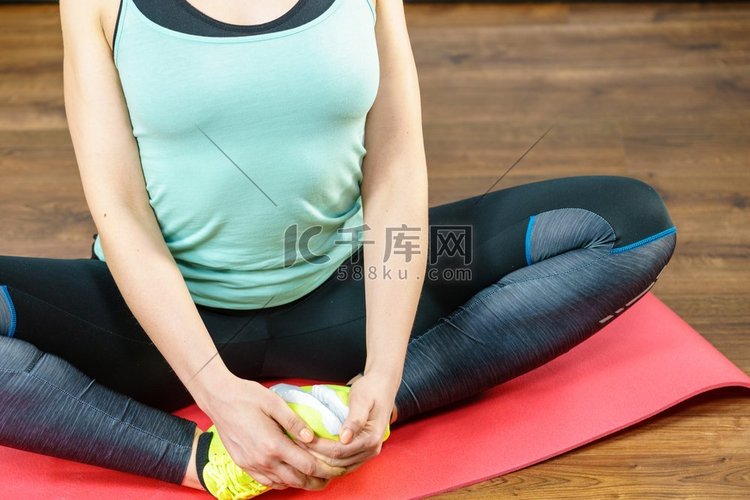 妇女在运动服坐在木地板室内伸展