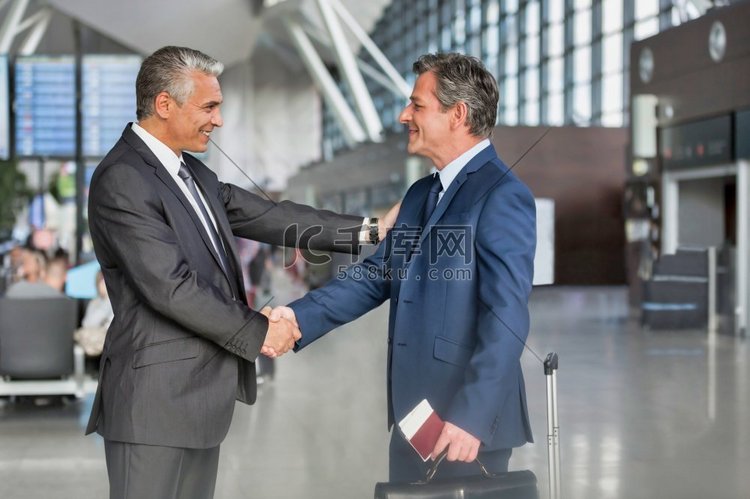 成熟商人在机场与商业伙伴握手