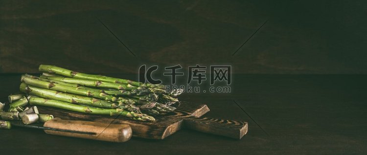 绿色芦笋在木砧板与刀在黑暗的乡