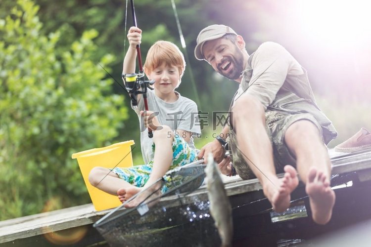 完整长度的微笑父亲和儿子捕捉鱼