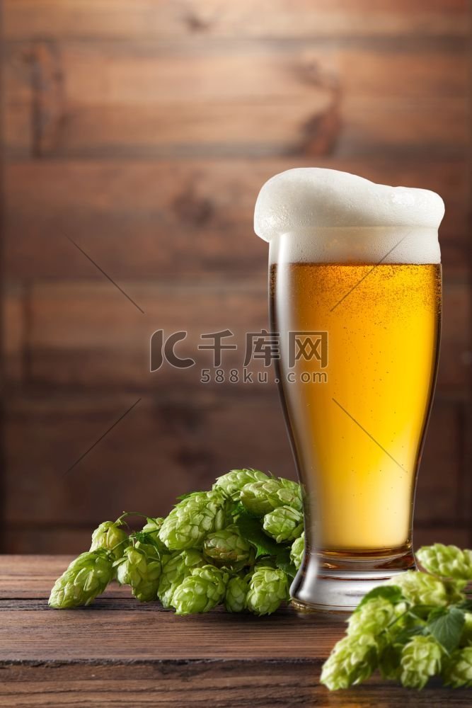 啤酒和啤酒花小桶在棕色木背景。