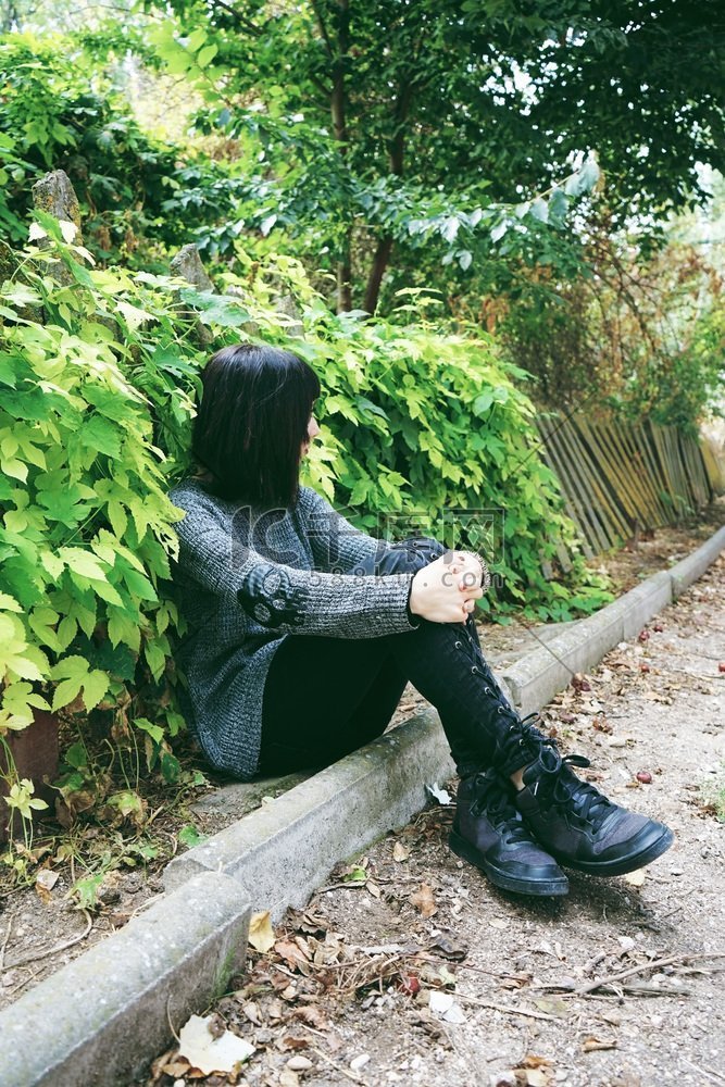 美丽的高加索黑发女子坐在公园的