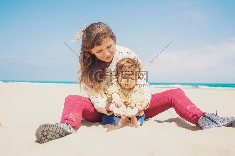 年轻的妈妈玩在海滩与她的孩子