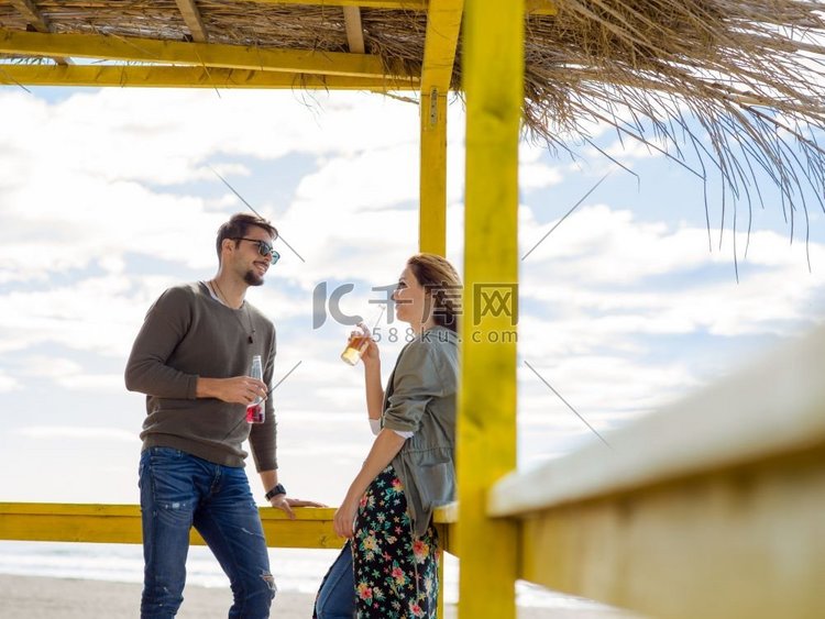 夫妇一起喝啤酒在空的海滩酒吧在