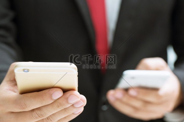 商人用两只手用手机或智能手机传