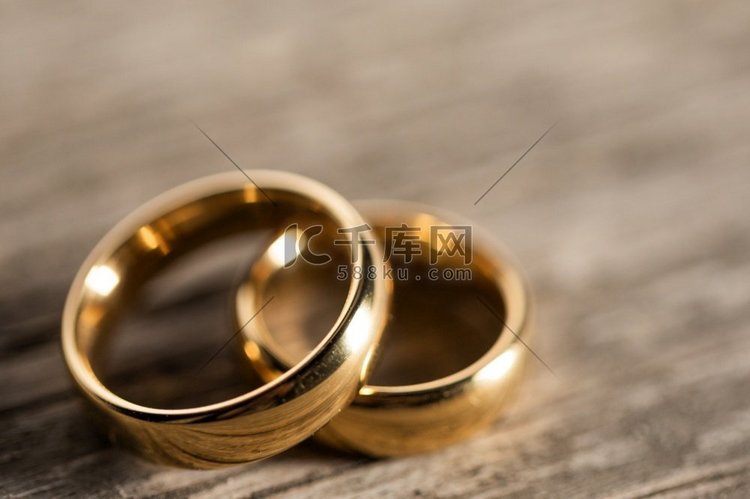木质背景上的两枚金色结婚戒指。