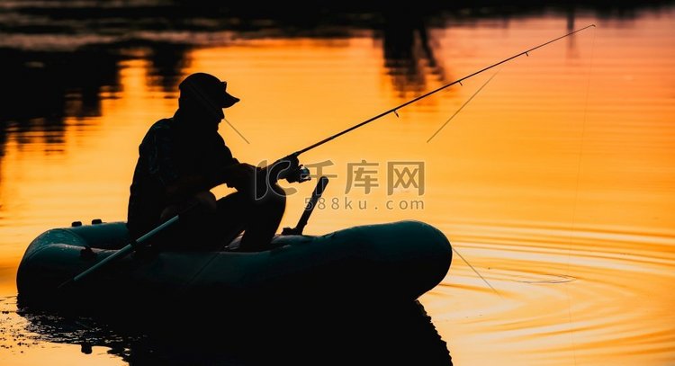 渔夫剪影在一条船捕鱼在湖在日落