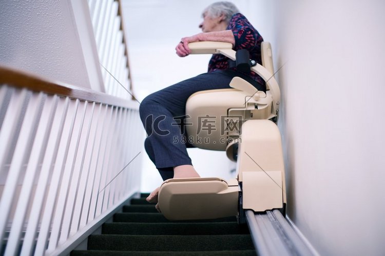 老年妇女坐在楼梯电梯在家里，以