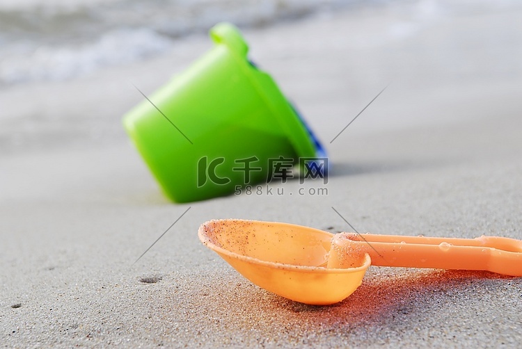 小孩子们在海边用木桶和勺子挖东