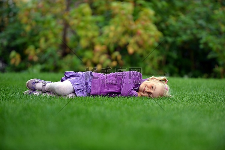 美丽快乐的小女孩躺在绿色的草地