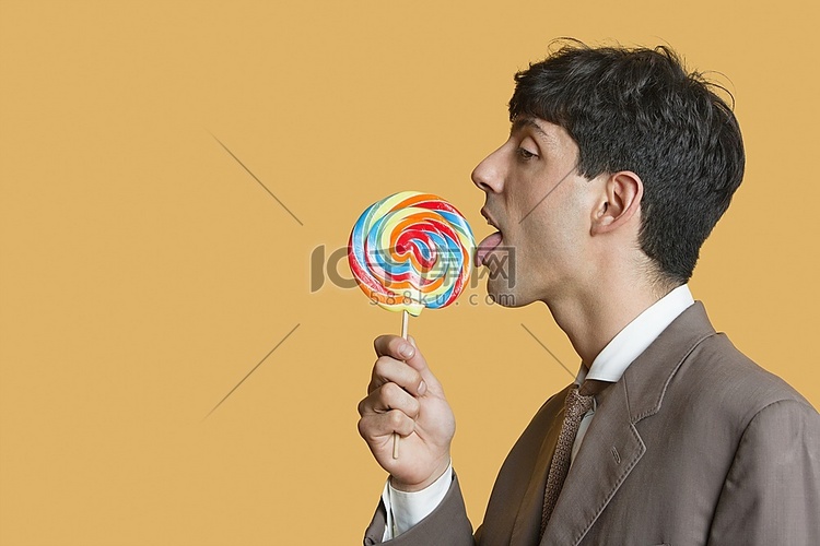 年轻商人在彩色背景上舔棒棒糖的
