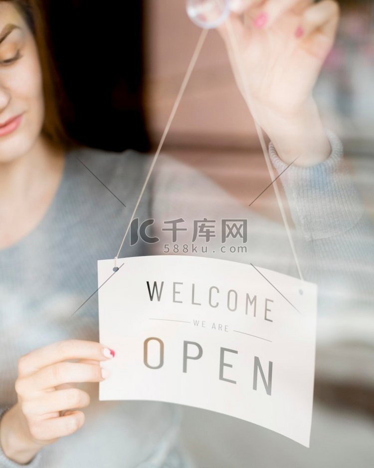 女人把打开的招牌放在橱窗咖啡店