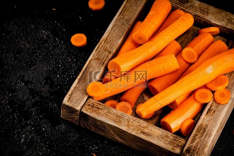 新鲜胡萝卜放在木托盘上。黑色背