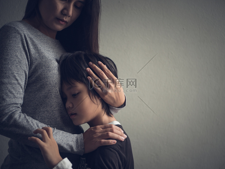 伤心的小男孩被抱着由他的母亲在