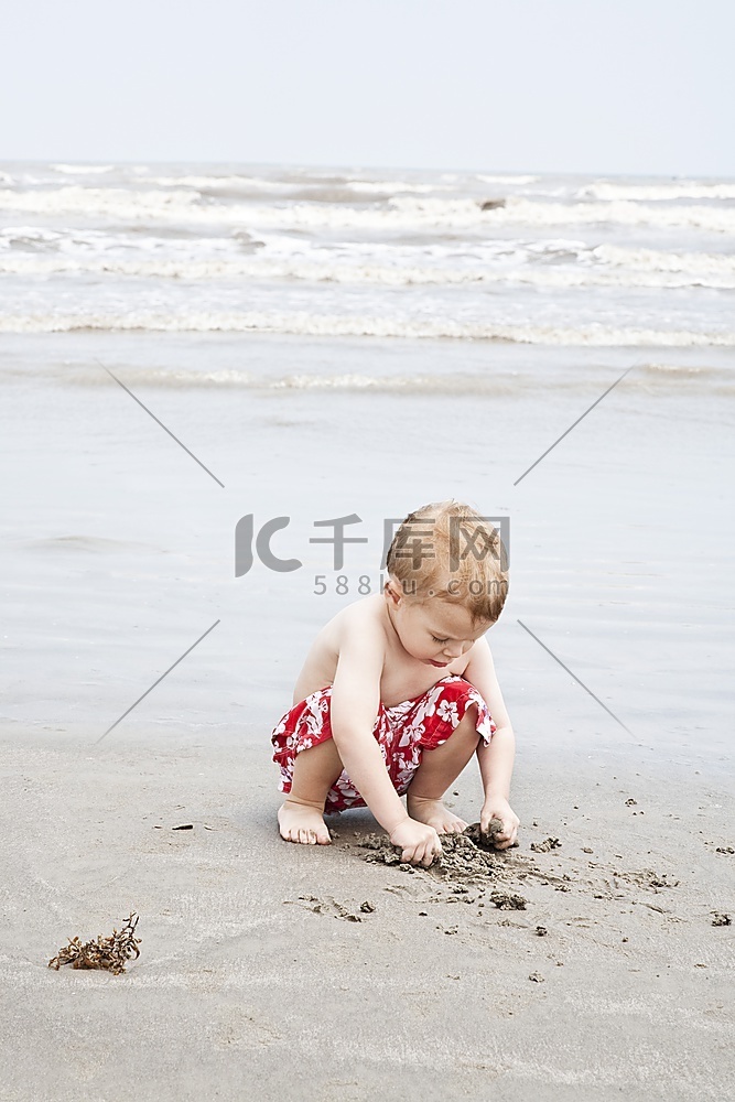 蹲在水中玩沙的男孩&锐利；S边缘