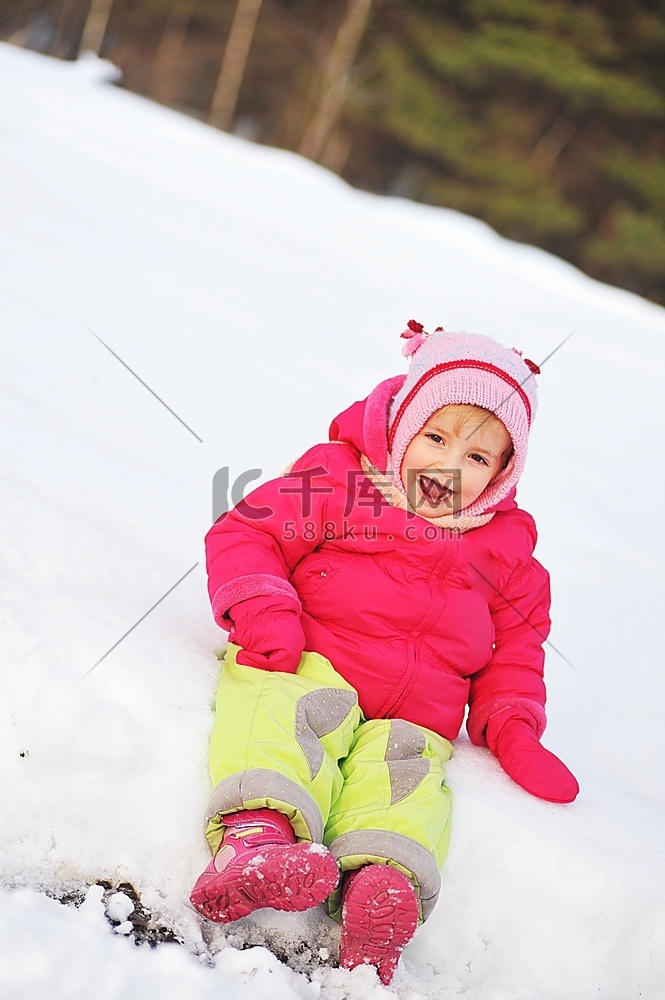 穿着冬大衣的小女孩坐在雪地上