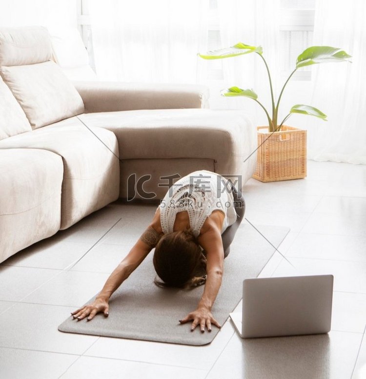 在笔记本电脑地板上做瑜伽的女人