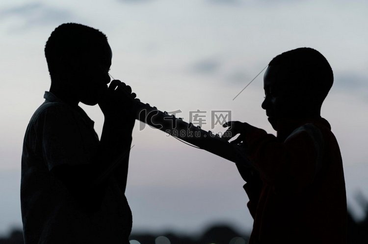 两个非洲儿童日落演奏乐器
