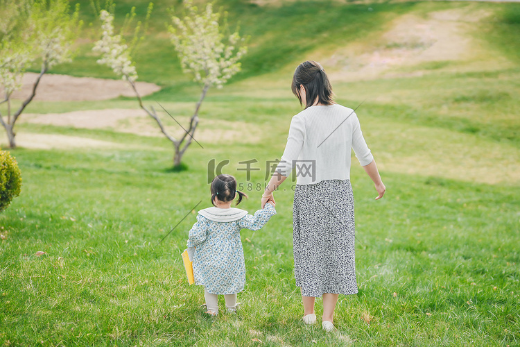 妈妈和孩子牵手的背影在草坪上