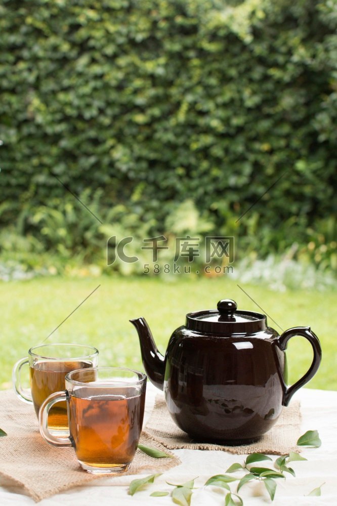 两个透明杯花草茶与茶壶桌花园。