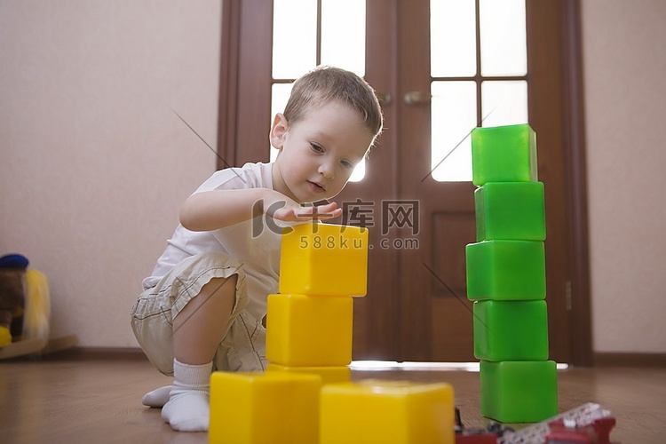 一个小男孩玩着绿色和黄色的建筑