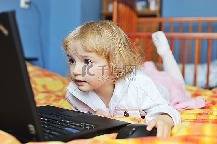 漂亮的小女孩拿着笔记本电脑躺在