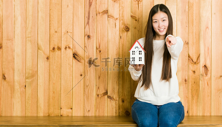年轻的亚洲女人拿着一栋房子，像