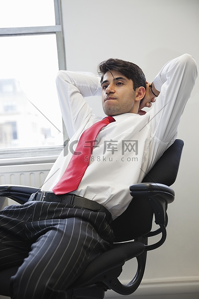 一位年轻的印度商人坐在办公椅上