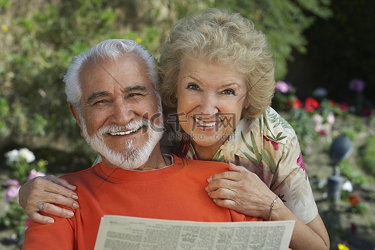 一对老年夫妇在花园里看报纸，肖