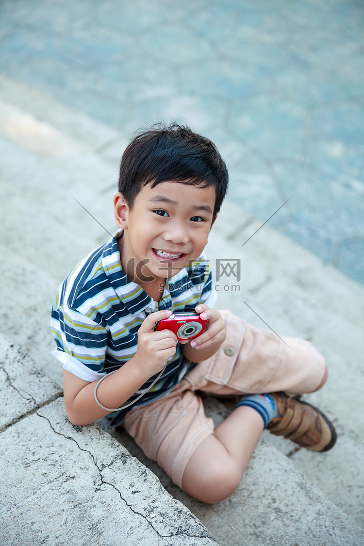 快乐的亚洲男孩，用相机在一天时