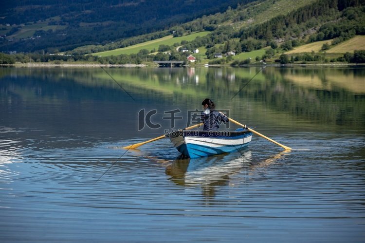 一名女子在船上钓鱼。挪威自然风