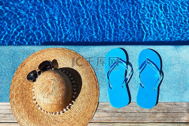 游泳池边的蓝色拖鞋和帽子