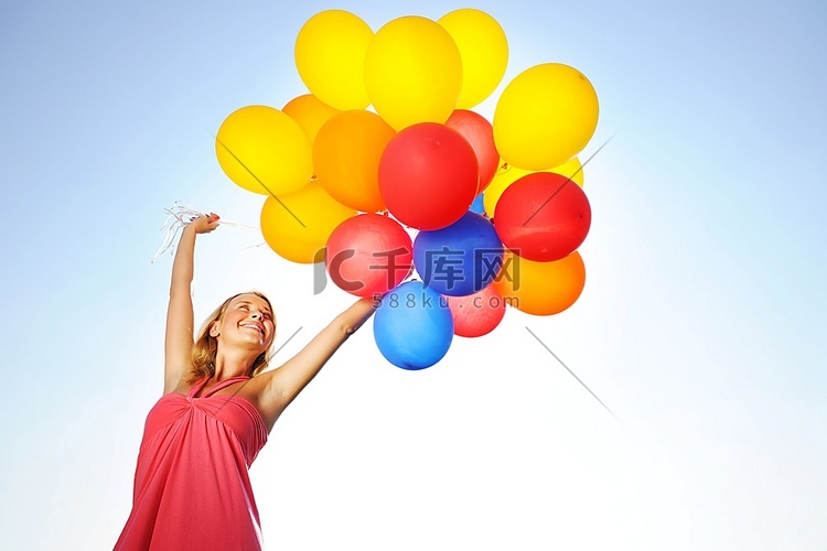 拿着气球顶着太阳和天空的女人