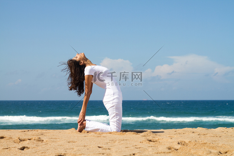 年轻健康的女性做瑜伽在海滩上