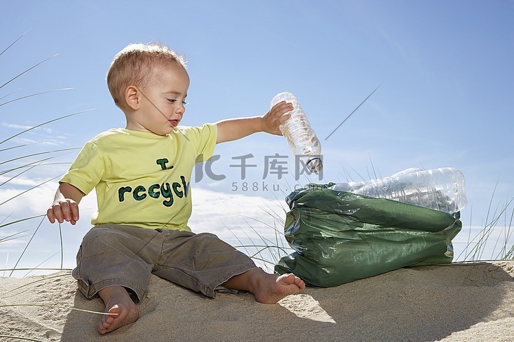 男孩(1-2)在沙丘上玩塑料瓶